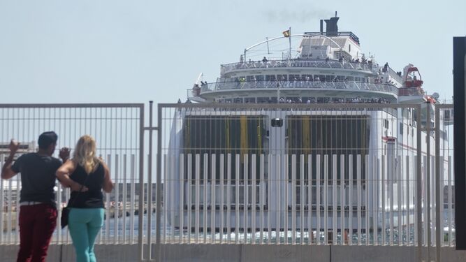Dos personas observan un ferry  repleto de pasajeros a punto de salir del Puerto de Motril